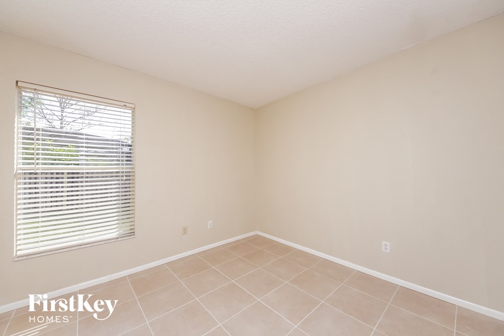 a bedroom with a large window and a tiled floor