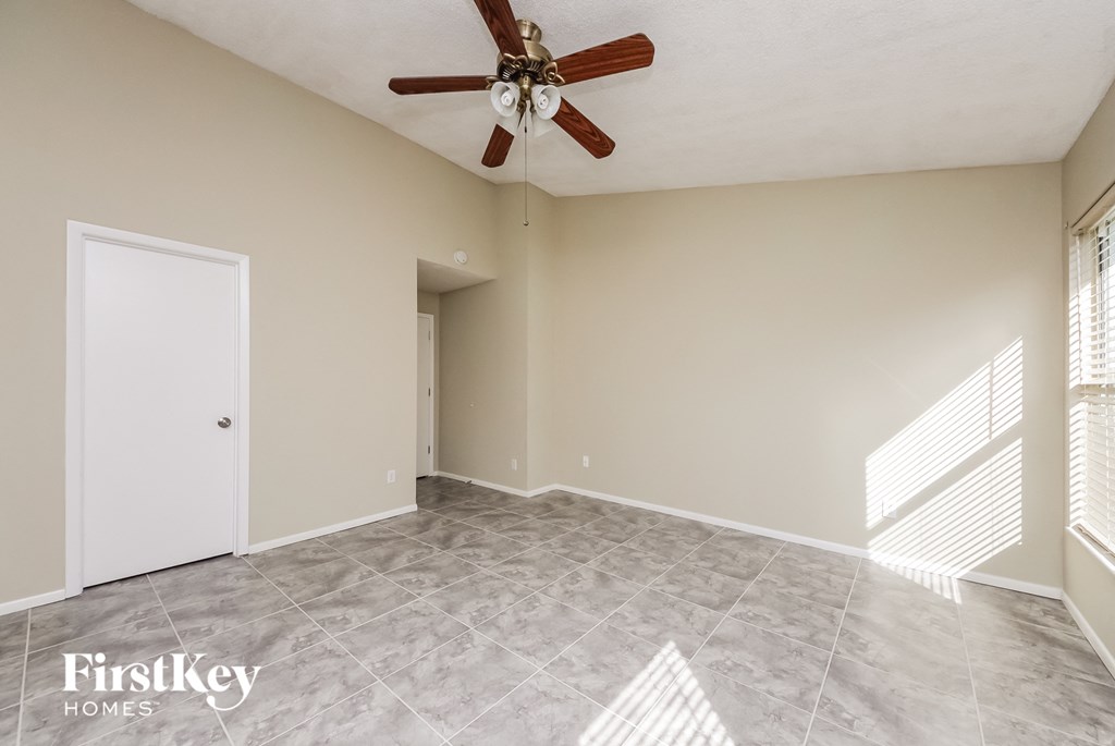 an empty living room with a ceiling fan and tile floor