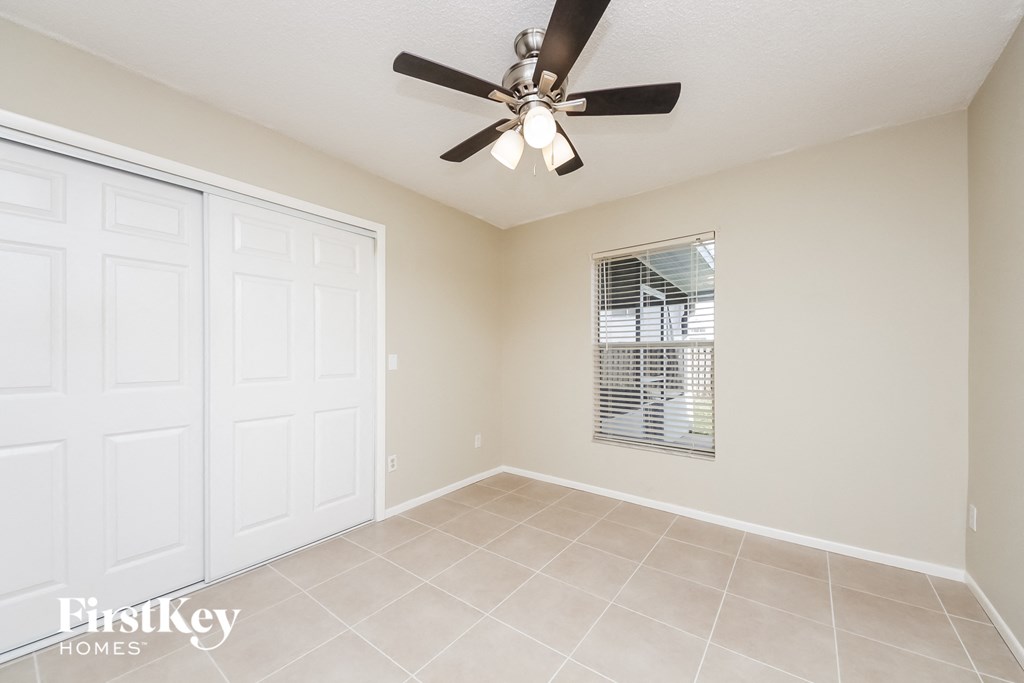 an empty living room with a ceiling fan and two closets