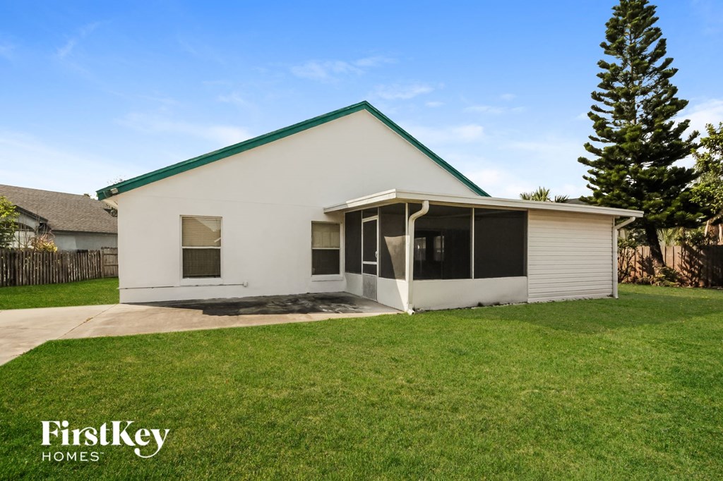 a white house with a green roof and a lawn