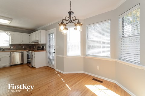 a kitchen with white cabinets and a wood floor and a chandelier