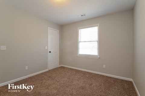 a bedroom with carpet and a door and a window