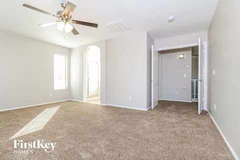 a spacious living room with carpet and a ceiling fan