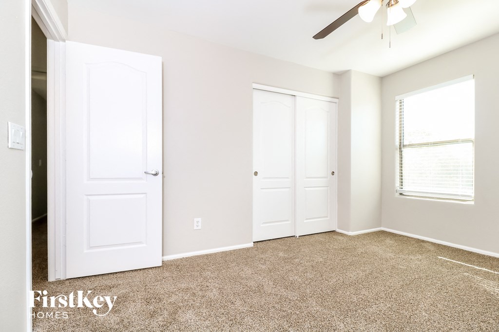 a bedroom with white doors and carpet and a ceiling fan