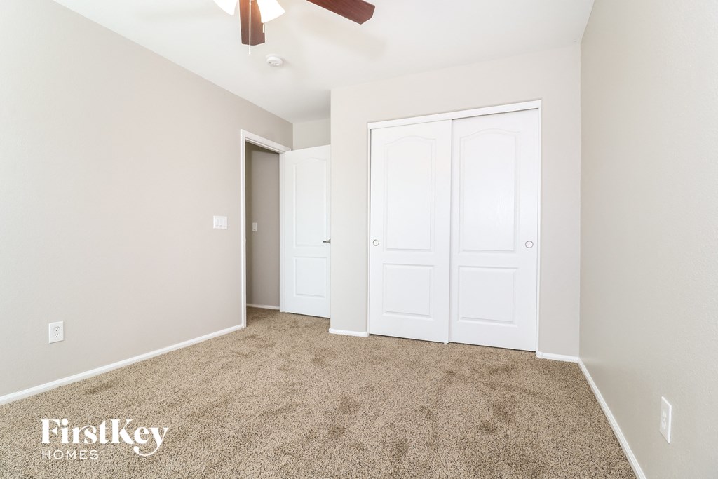 a bedroom with white doors and carpet and a ceiling fan