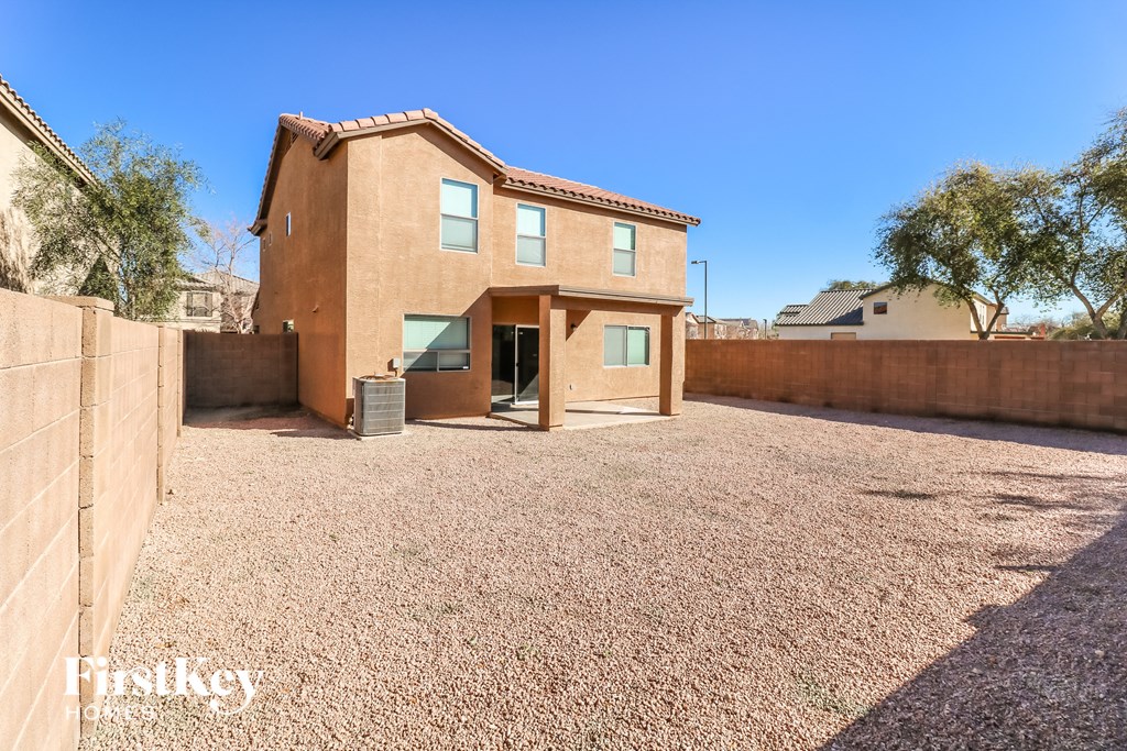a southwestern home with a gravel driveway and a gate