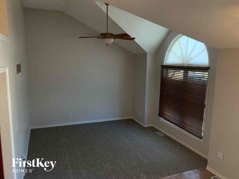 an empty living room with a ceiling fan and a window