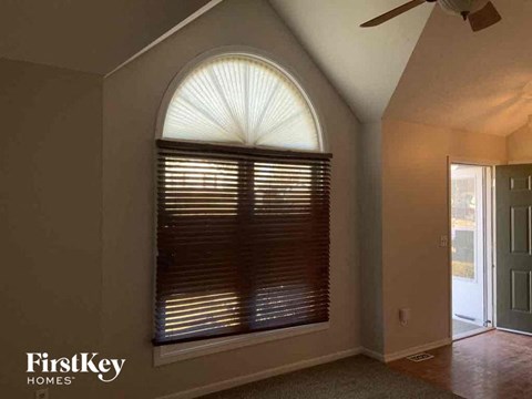 a living room with a large arched window and a ceiling fan