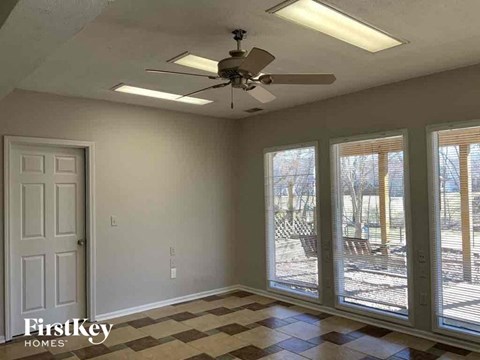 an empty living room with a ceiling fan and a window
