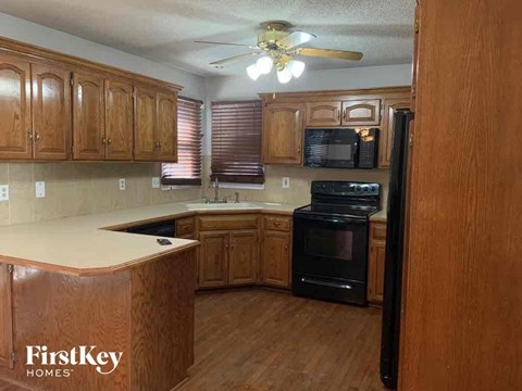 a kitchen with wooden cabinets and a black stove and a ceiling fan