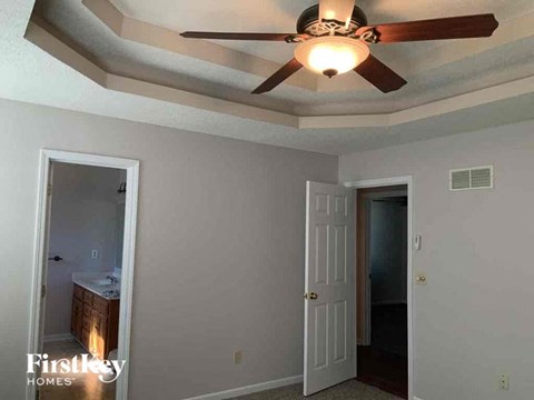 a bedroom with a ceiling fan and a door to a bathroom