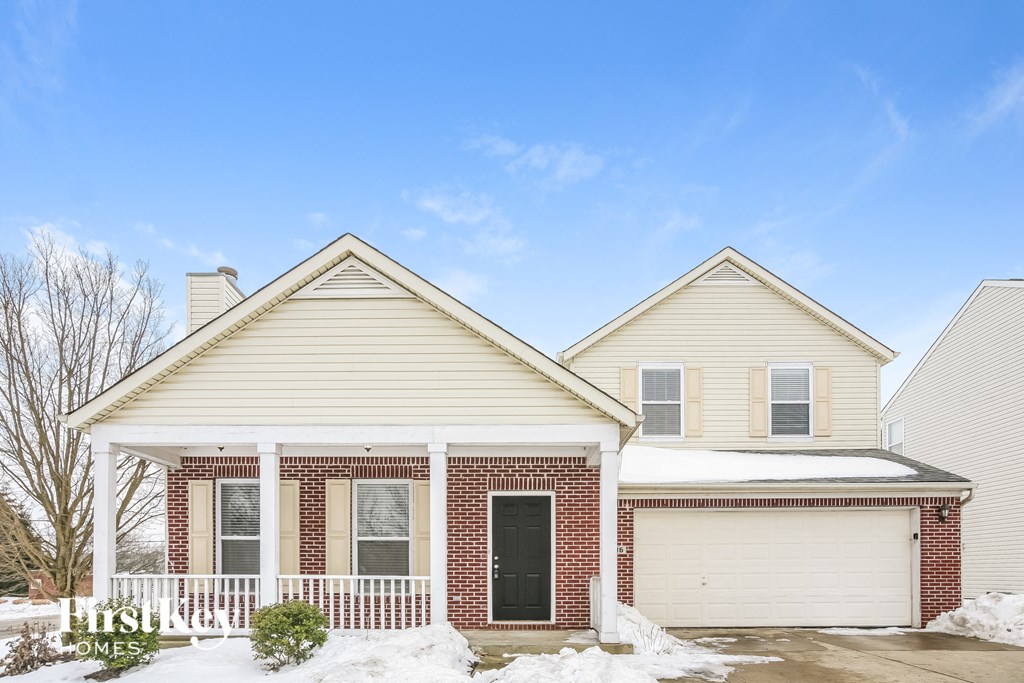 a white and brick house with snow on the ground