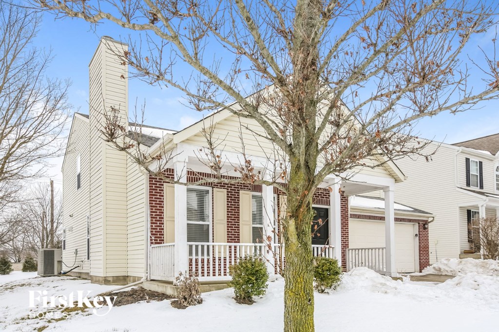a white house with a tree in the snow