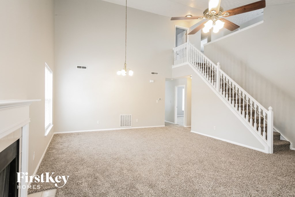 an empty living room with a ceiling fan and a staircase