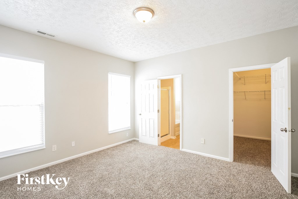 a bedroom with a carpeted floor and a door to a closet