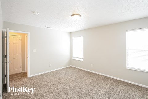 a bedroom with carpet and a door and a window
