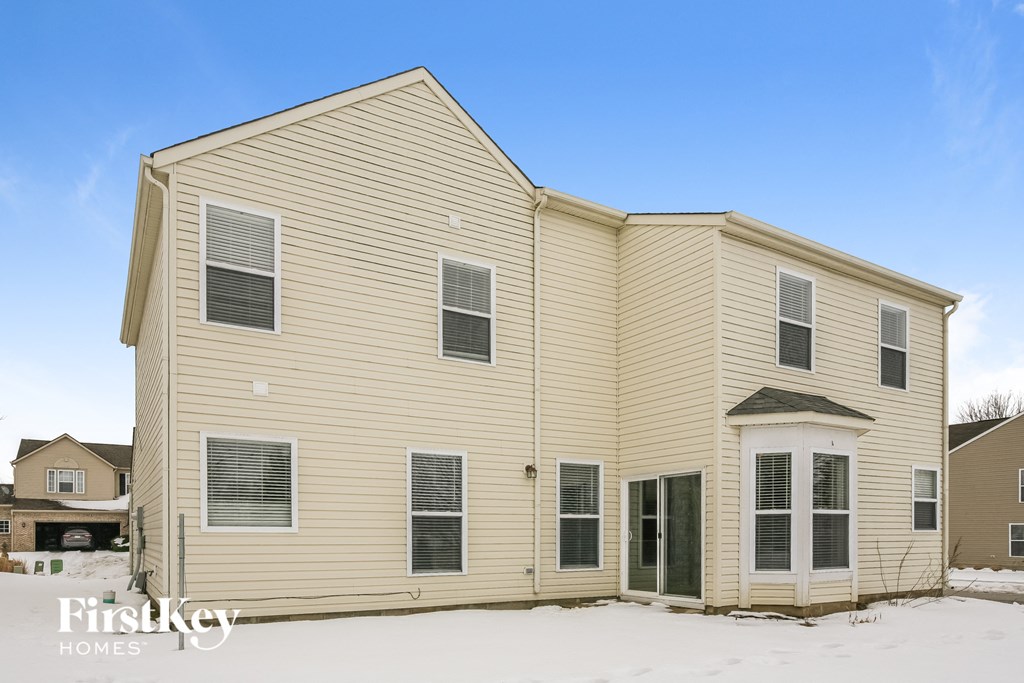a home with yellow siding and snow on the ground