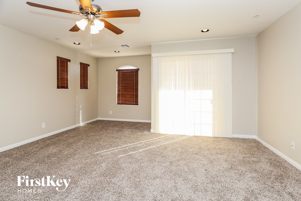 a empty living room with a ceiling fan and a window
