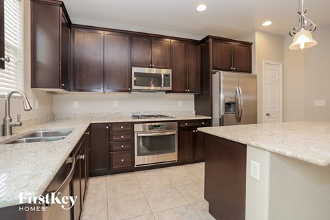 A kitchen with brown cabinets and a marble countertop.