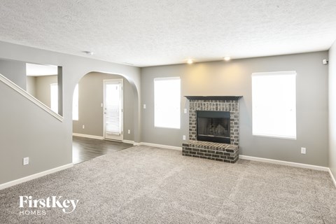 A spacious living room with a fireplace and a carpeted floor.