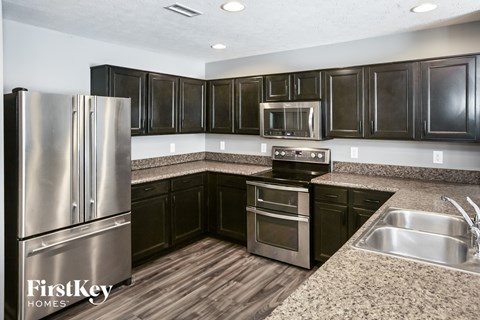 A kitchen with a stainless steel refrigerator and black cabinets.