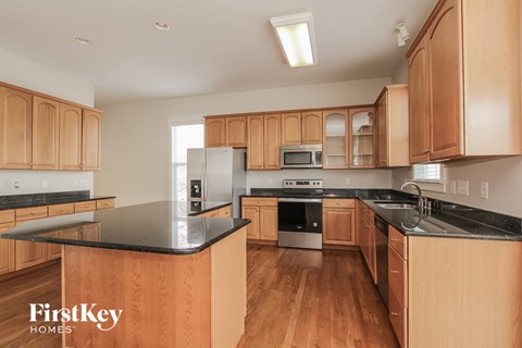 a large kitchen with wooden cabinets and black counter tops and stainless steel appliances