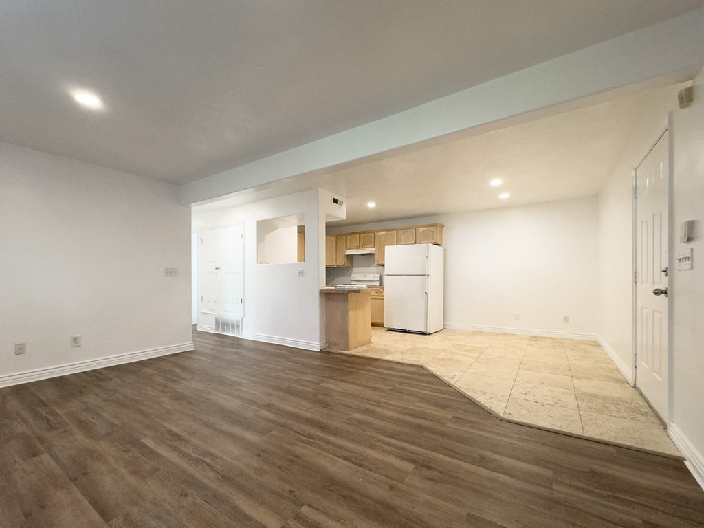the living room and kitchen of a new home with white walls and wood flooring