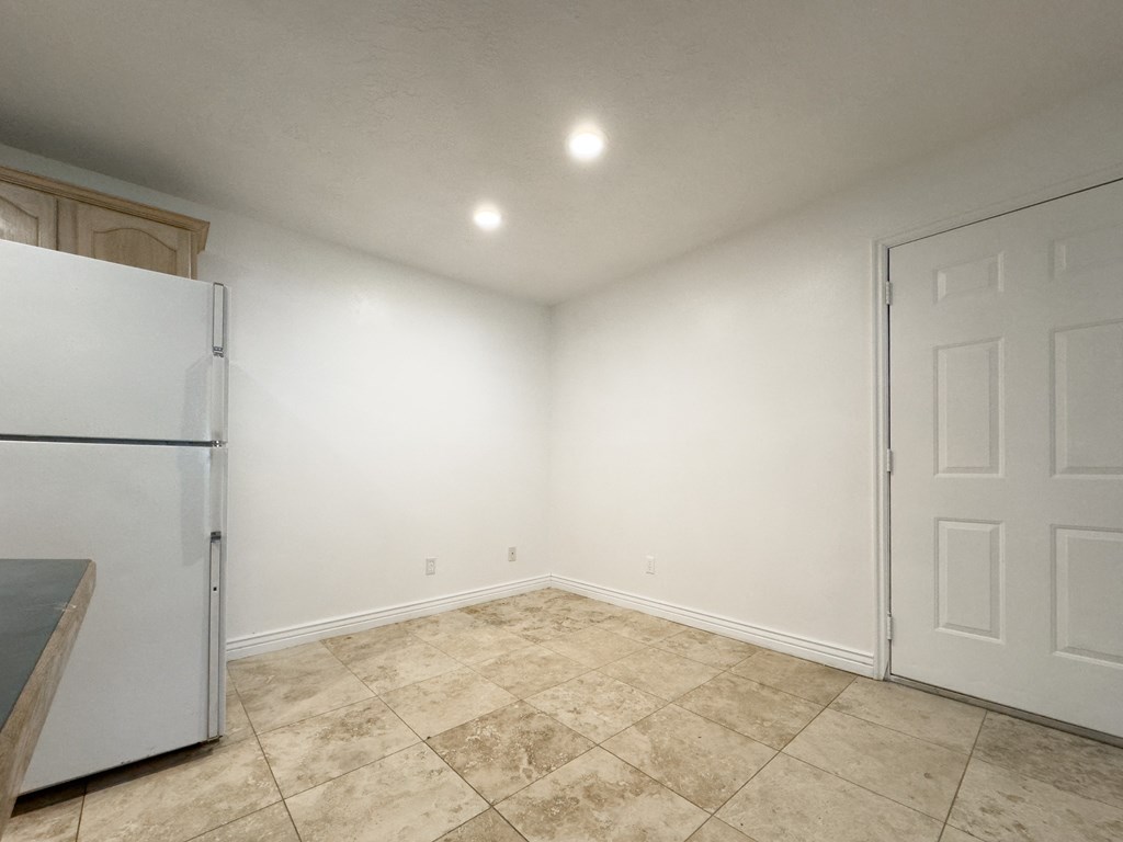 an empty room with a refrigerator and a door