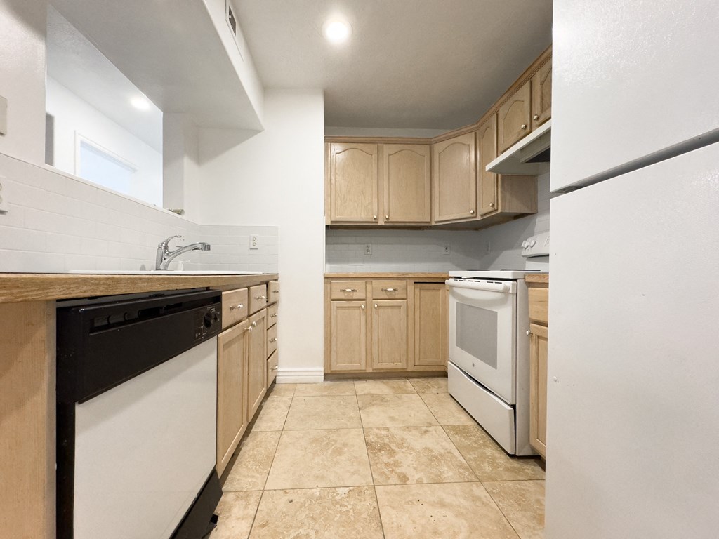 an empty kitchen with white appliances and wooden cabinets