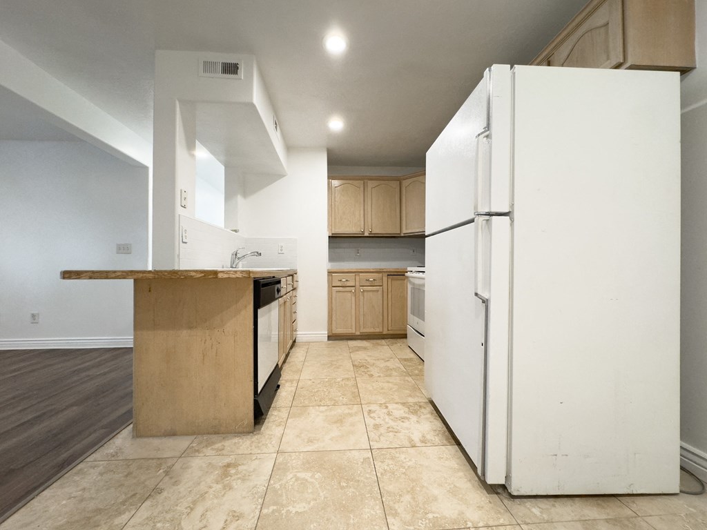 an empty kitchen with a white refrigerator and a counter top