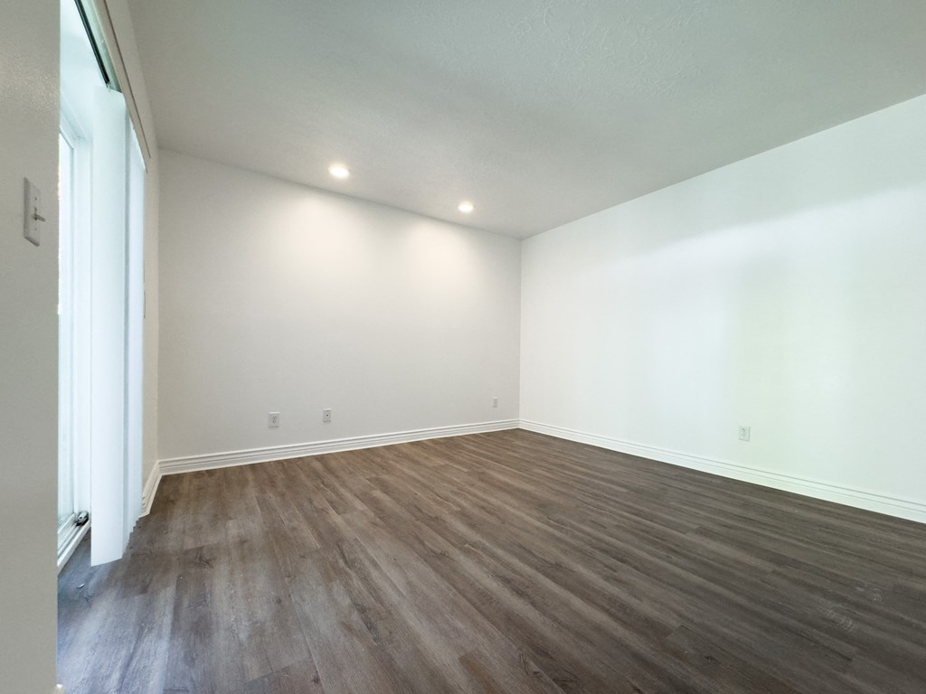 an empty living room with white walls and wood flooring