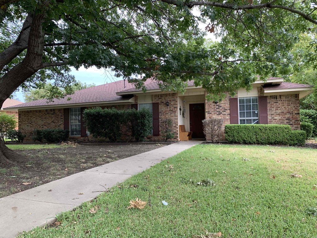 a house with a sidewalk and a tree in front of it