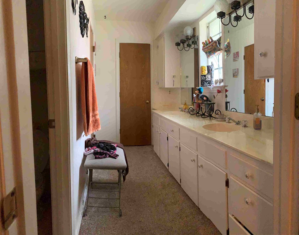 a bathroom with white cabinets and a sink and a stool
