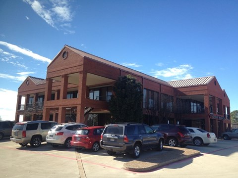 A parking lot with cars and a building in the background.