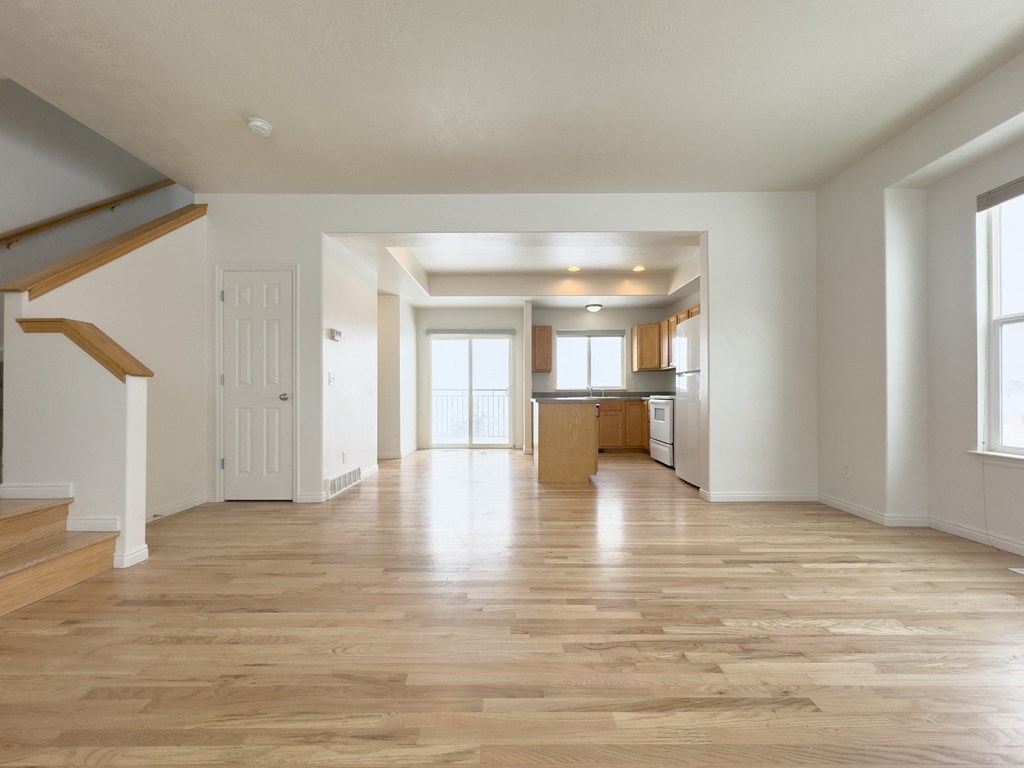 the living room and kitchen of an empty house with wood floors