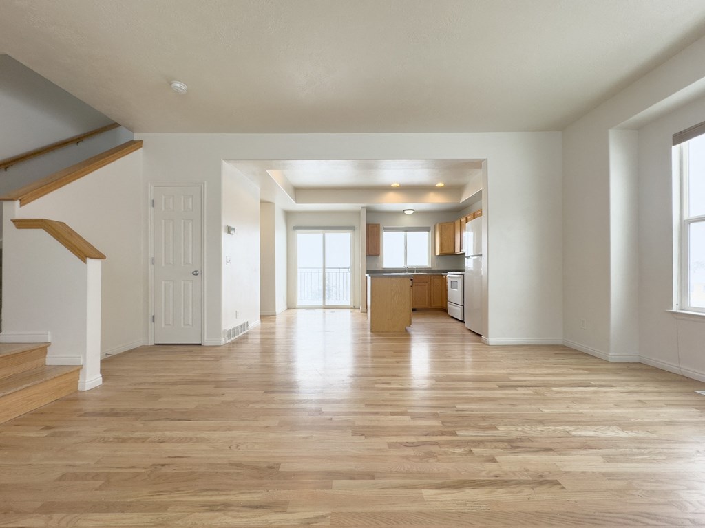 the living room and kitchen of an empty house with wood floors