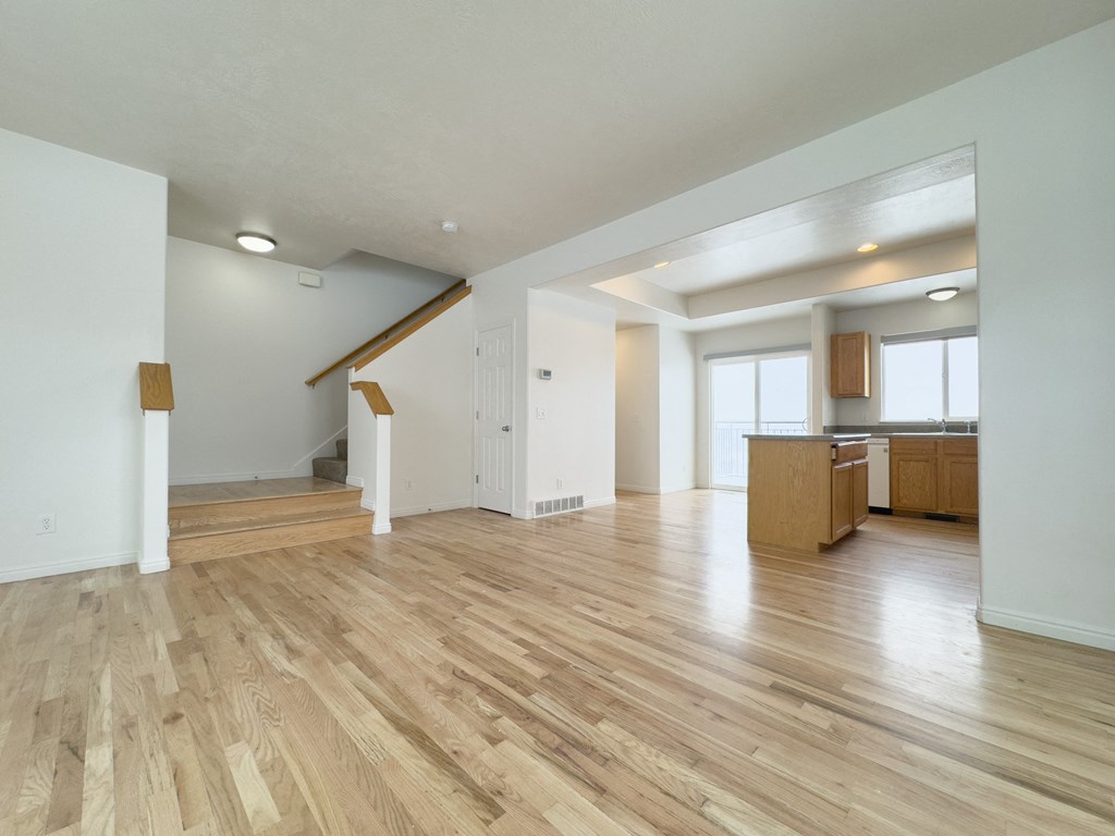 the living room and kitchen of an empty home with wood flooring