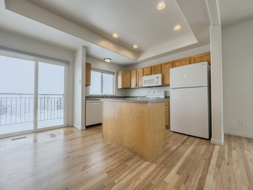 a kitchen with a island and a refrigerator and a door to a balcony
