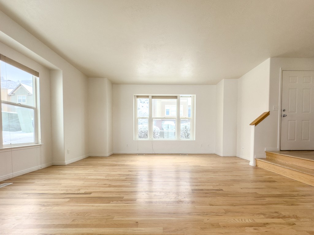 an empty living room with hard wood floors and a window