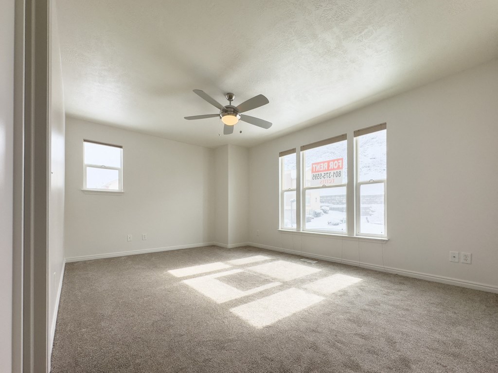 an empty living room with a ceiling fan and a window