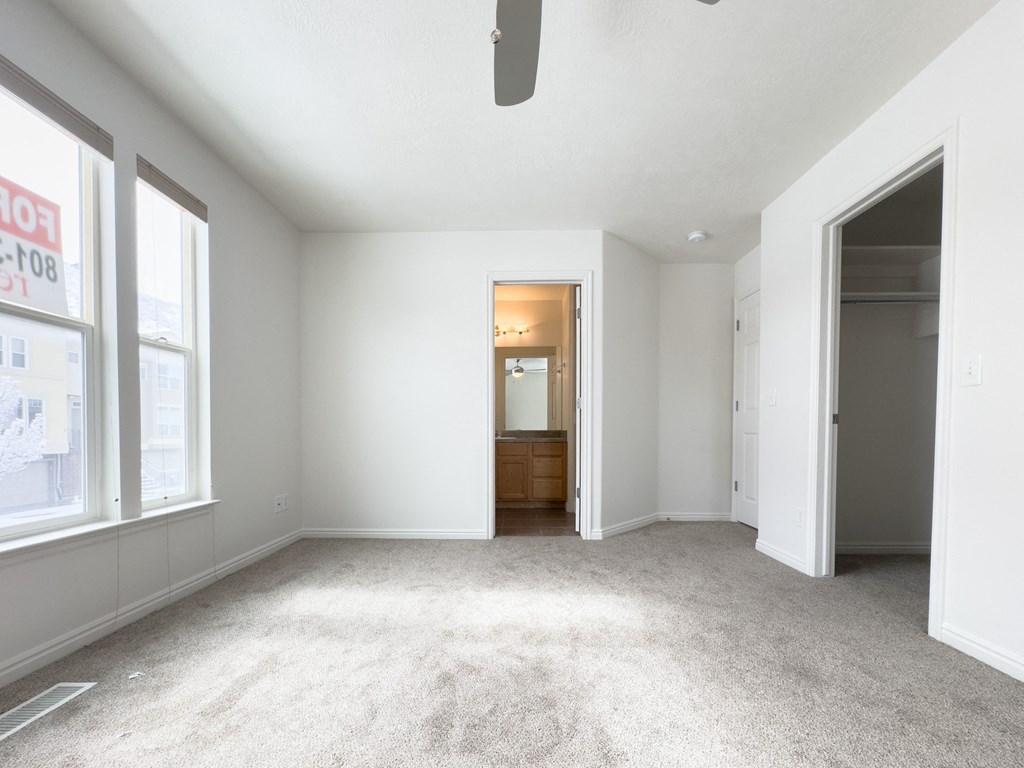 an empty living room with large windows and a carpeted floor