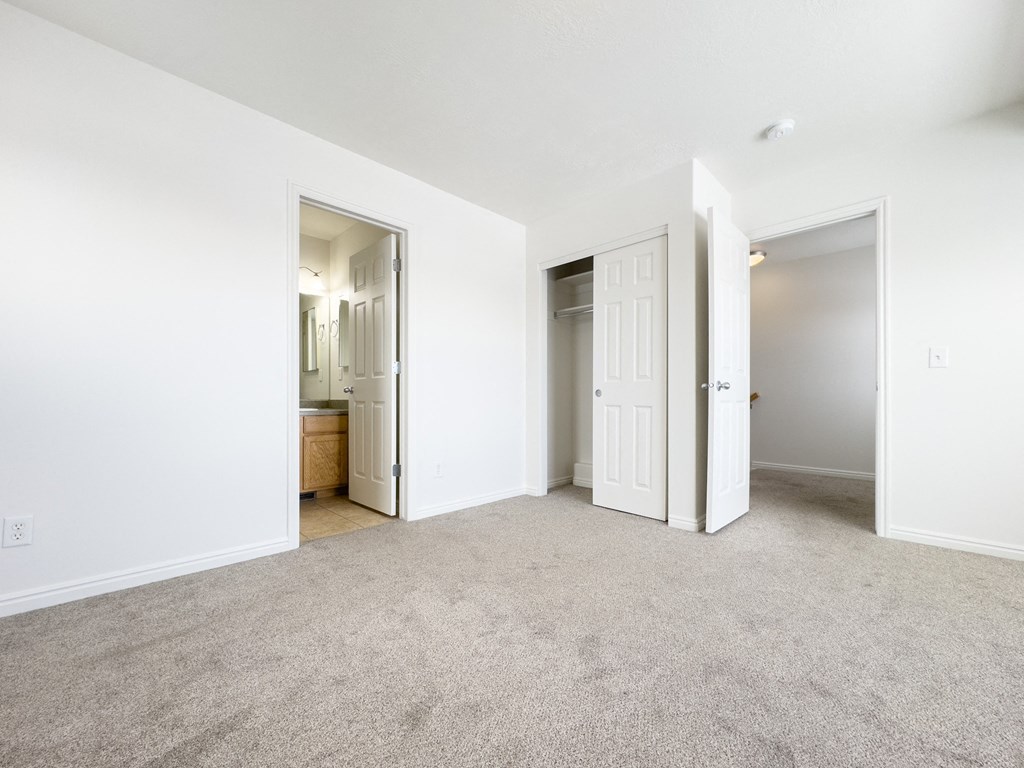 an empty living room with a door to a bathroom and a closet
