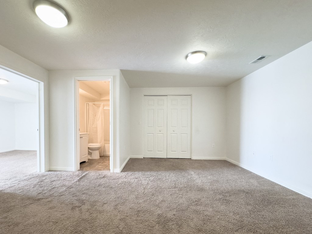 an empty living room with a door to a bathroom