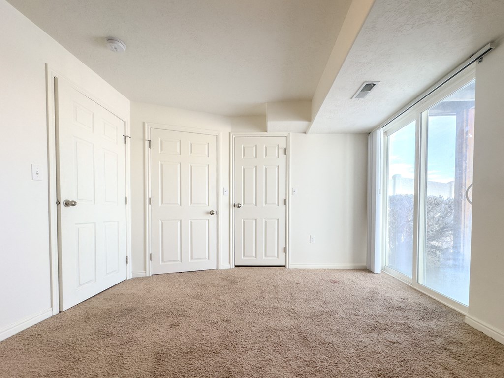 an empty living room with two doors and a window