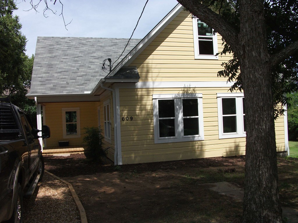 a yellow house with a tree in front of it