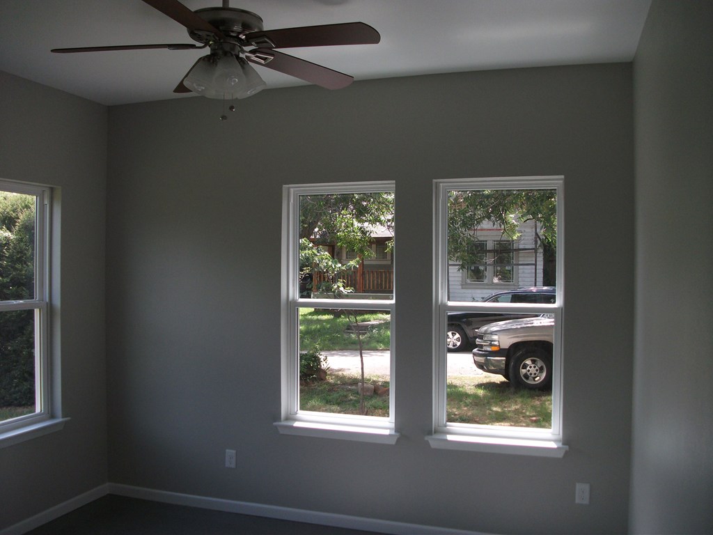 three windows in a living room with a ceiling fan