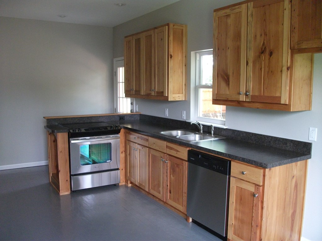 an empty kitchen with wooden cabinets and a stove and a sink