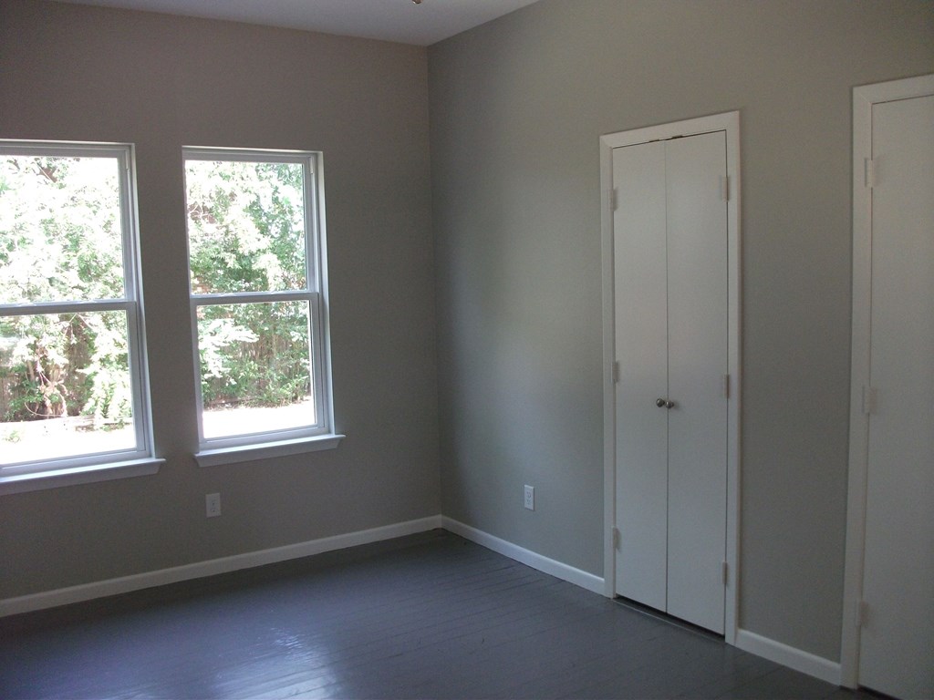 an empty room with two windows and a door
