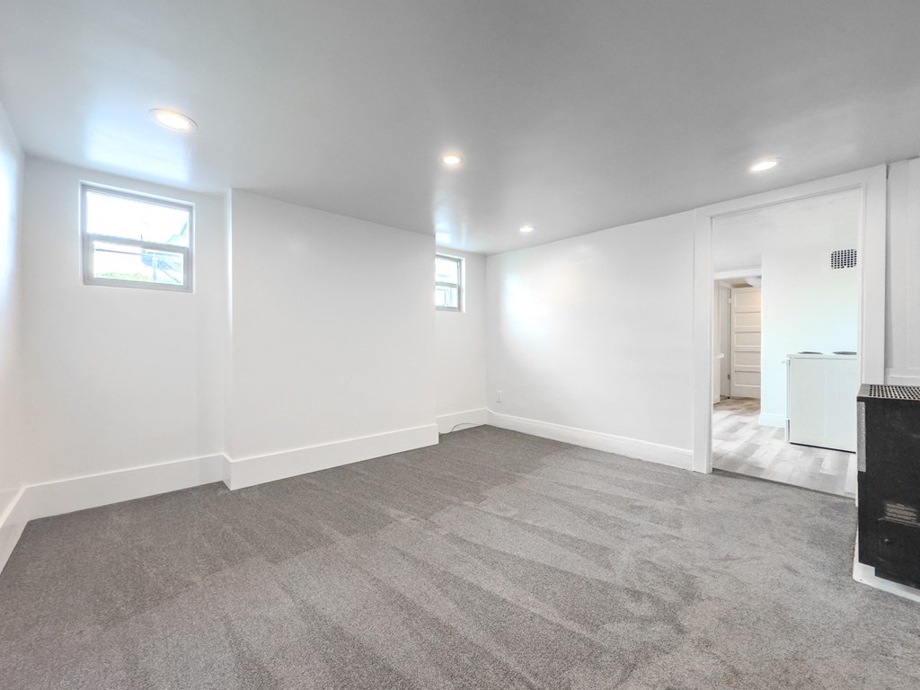 an empty living room with a fireplace and white walls