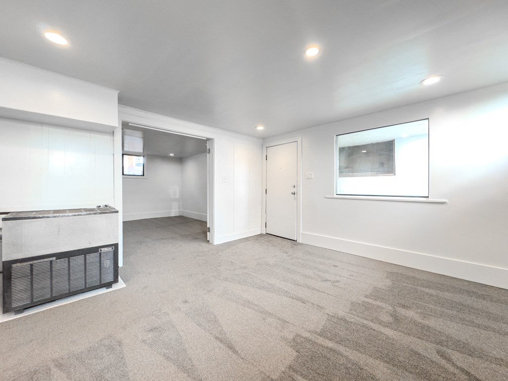 a living room with white walls and a fireplace and a window